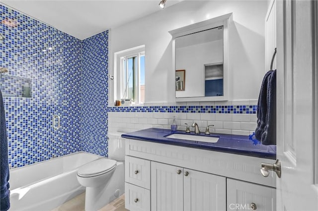 full bathroom featuring vanity, tile walls, toilet, and shower / washtub combination