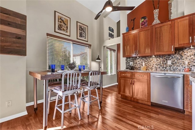 kitchen with backsplash, dark wood-type flooring, brown cabinetry, a ceiling fan, and stainless steel dishwasher