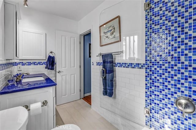 bathroom with a shower stall, tile walls, and vanity