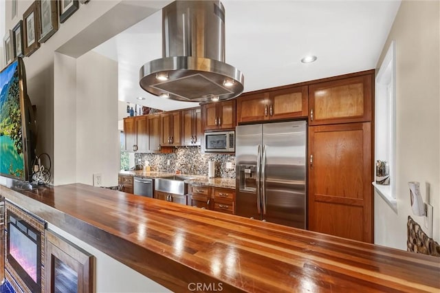 kitchen with backsplash, appliances with stainless steel finishes, island exhaust hood, wood counters, and a sink