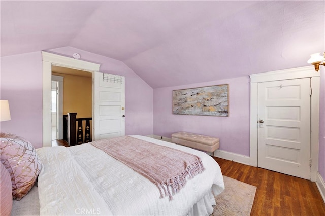 bedroom with baseboards, lofted ceiling, and wood finished floors