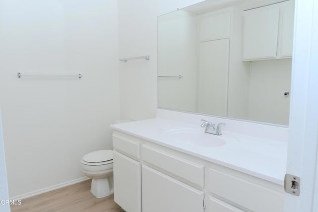 bathroom featuring vanity, toilet, wood finished floors, and baseboards