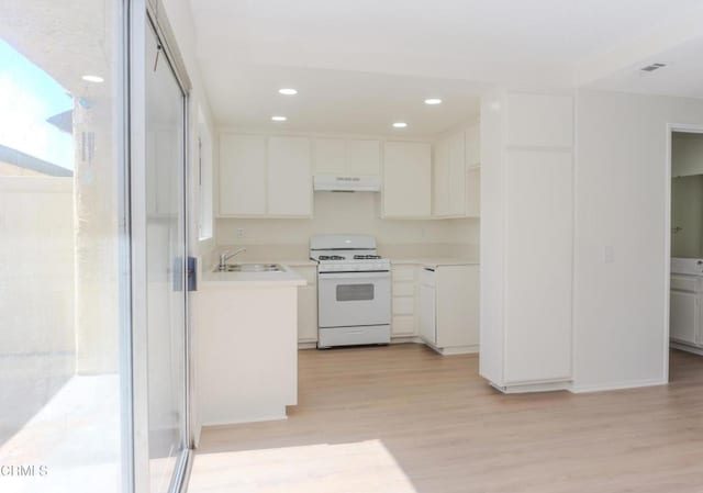 kitchen featuring under cabinet range hood, white range with gas stovetop, white cabinets, and light wood finished floors