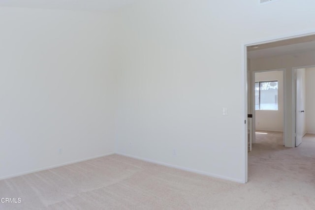 empty room featuring baseboards and light carpet