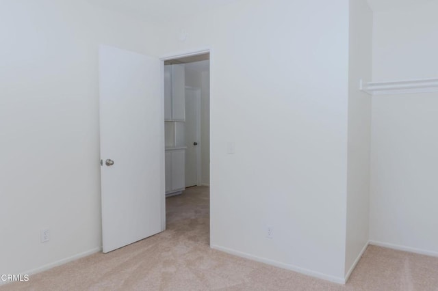 unfurnished room with baseboards and light carpet