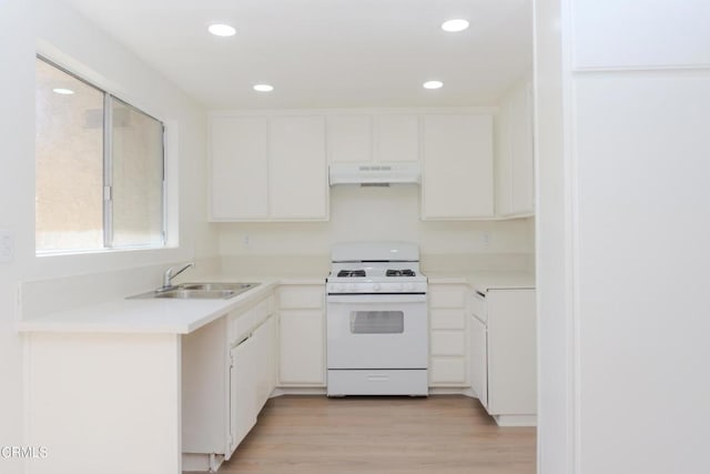 kitchen featuring under cabinet range hood, a sink, white cabinets, and white gas range oven