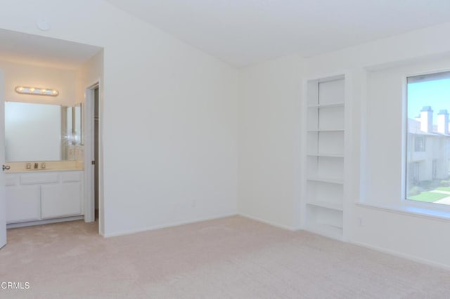 unfurnished bedroom with baseboards, light carpet, a closet, and ensuite bathroom