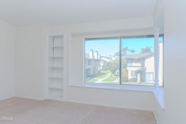 spare room with built in shelves, baseboards, and carpet floors