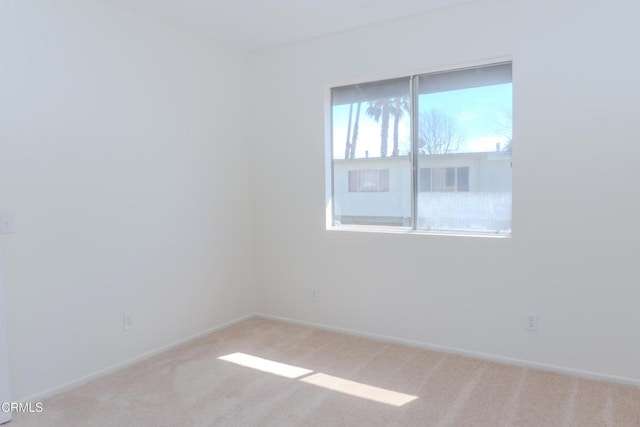 carpeted empty room featuring baseboards