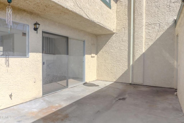 view of exterior entry featuring a patio and stucco siding