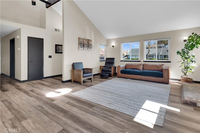 living area featuring baseboards, wood finished floors, visible vents, and high vaulted ceiling