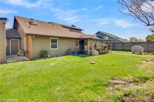 rear view of house with a patio, a lawn, and fence