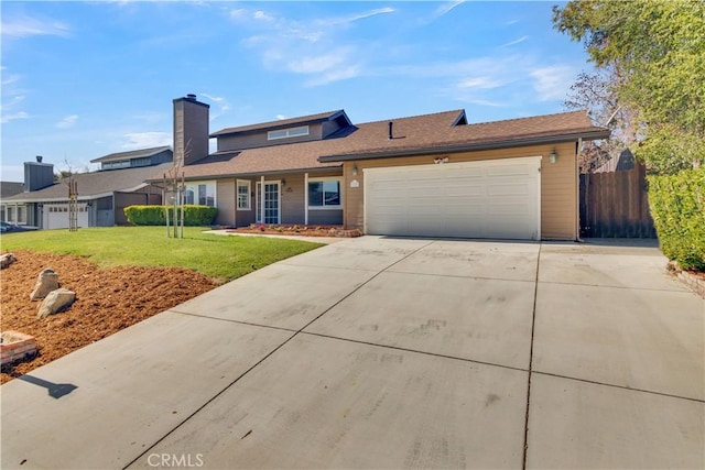 view of front facade with fence, concrete driveway, a front yard, a chimney, and a garage