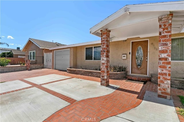 view of front of house with stucco siding, driveway, an attached garage, and fence