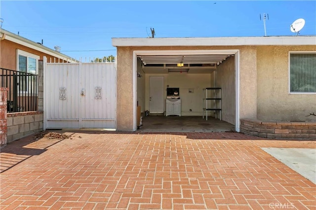 garage featuring a gate, decorative driveway, and fence