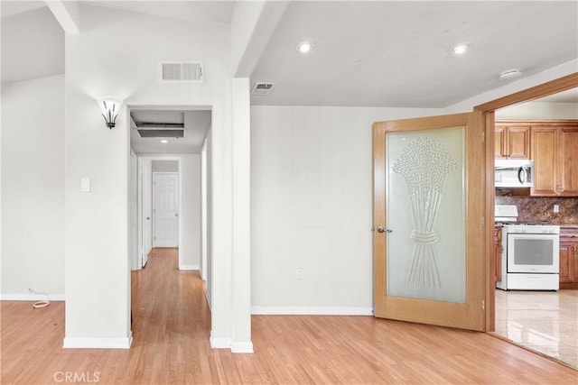 interior space with light wood-type flooring, visible vents, white gas stove, stainless steel microwave, and decorative backsplash