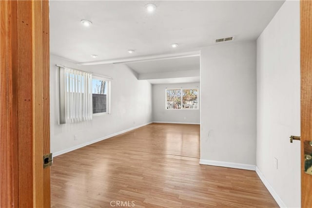 unfurnished room featuring visible vents, baseboards, and wood finished floors