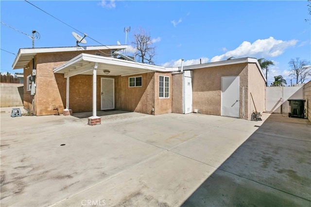 view of front of property featuring a gate, a patio area, fence, and stucco siding