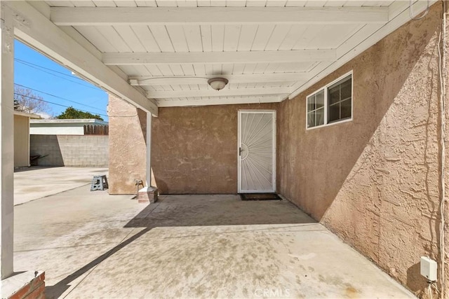 entrance to property featuring a patio area, stucco siding, and fence