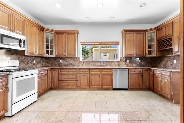 kitchen featuring decorative backsplash, brown cabinets, appliances with stainless steel finishes, and a sink