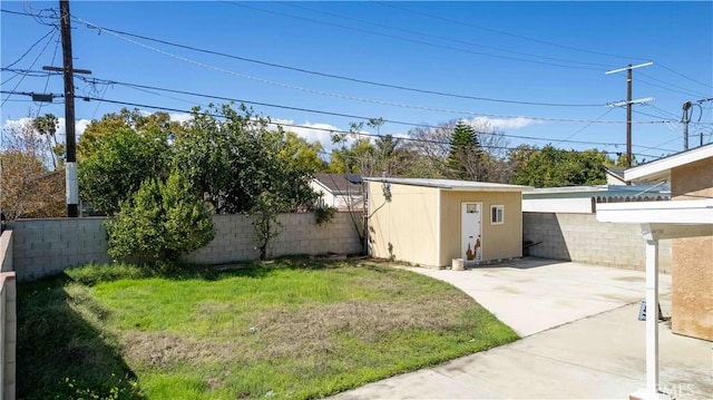 view of yard with an outbuilding, a shed, a patio area, and a fenced backyard