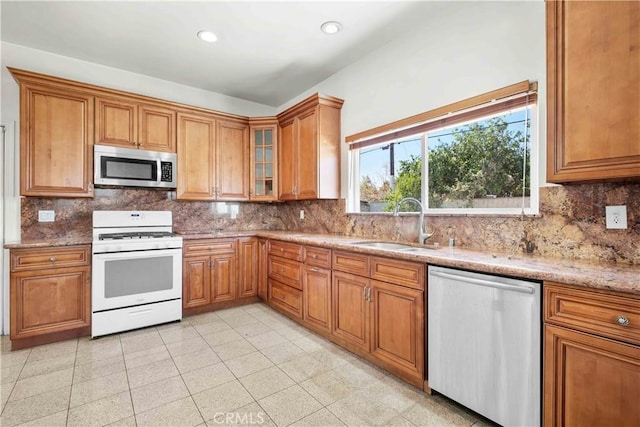 kitchen featuring backsplash, brown cabinets, stainless steel appliances, and a sink