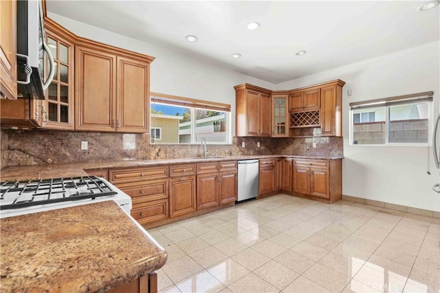 kitchen with baseboards, recessed lighting, brown cabinets, stainless steel appliances, and a sink