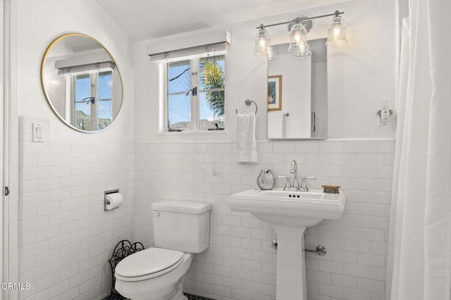 bathroom featuring toilet, tile walls, and wainscoting