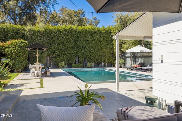 outdoor pool with fence and a patio area