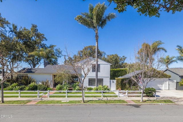 view of front facade featuring a garage, a chimney, a fenced front yard, and concrete driveway