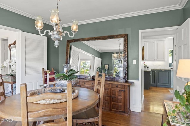 dining room with a chandelier, ornamental molding, and wood finished floors