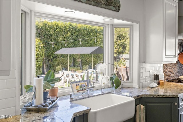 kitchen featuring light stone countertops, backsplash, and a sink