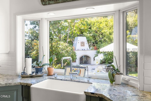 kitchen with light stone countertops, backsplash, and a sink