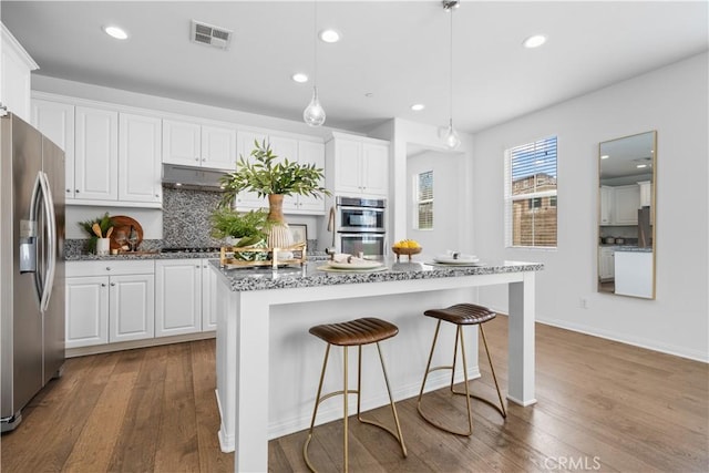 kitchen with visible vents, white cabinets, appliances with stainless steel finishes, and wood-type flooring