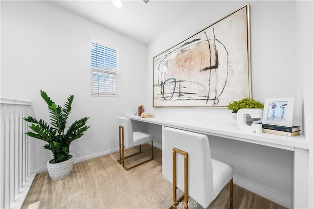 office area featuring light carpet, built in study area, and baseboards