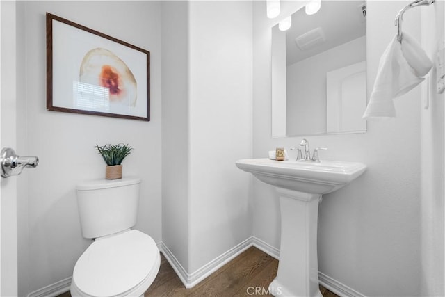 half bathroom with toilet, baseboards, and wood finished floors