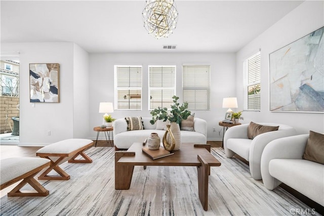 living room with baseboards, wood finished floors, visible vents, and a chandelier