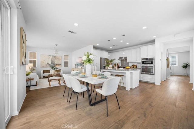 dining space with light wood finished floors, visible vents, and recessed lighting