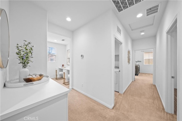 hall featuring visible vents, light colored carpet, and baseboards