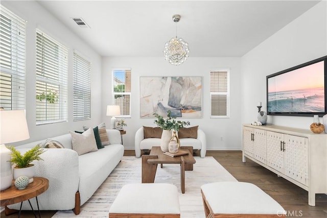 living room with a chandelier, visible vents, baseboards, and wood finished floors