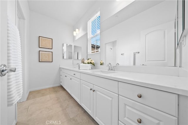 bathroom with a sink, baseboards, double vanity, and tile patterned flooring