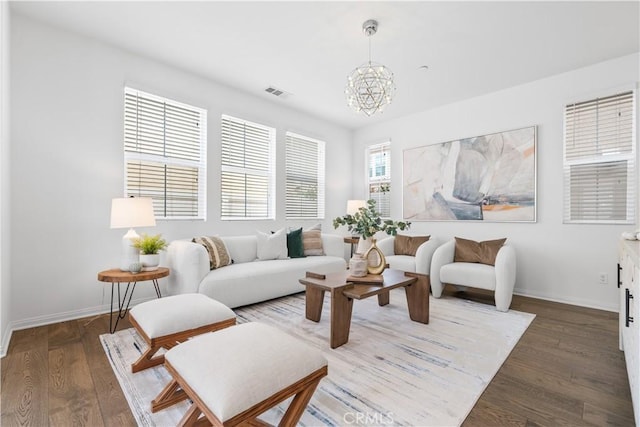 living room with visible vents, baseboards, an inviting chandelier, and wood finished floors