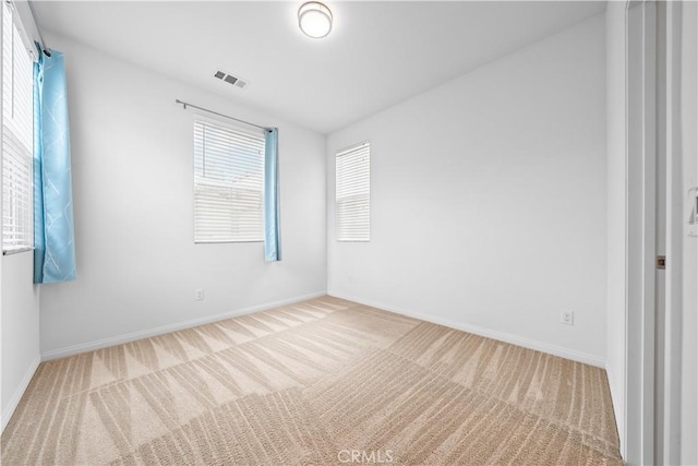 carpeted spare room featuring baseboards and visible vents