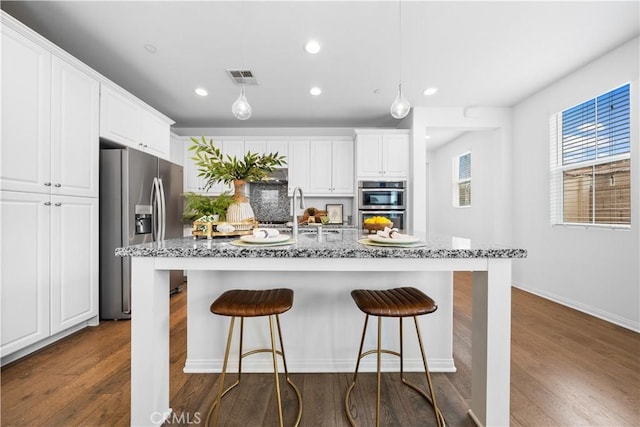 kitchen featuring dark wood-type flooring, a kitchen breakfast bar, visible vents, and stainless steel appliances