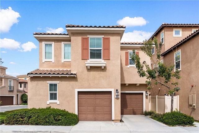 view of front of property with stucco siding, an attached garage, concrete driveway, and fence