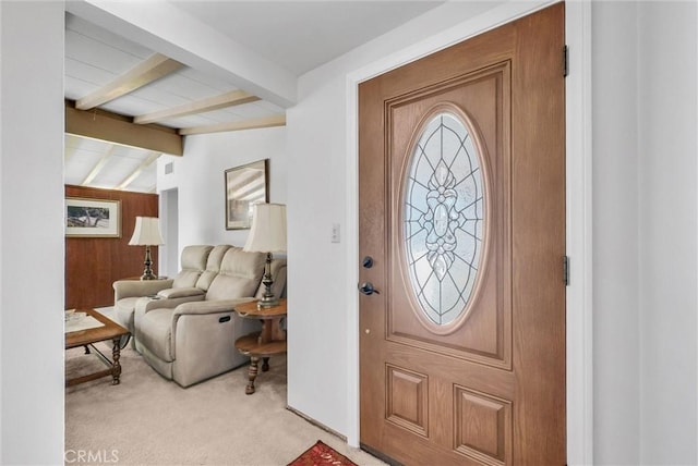 foyer entrance with vaulted ceiling with beams and light carpet