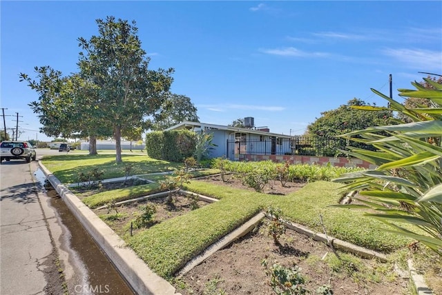 exterior space with fence, a front lawn, and a garden