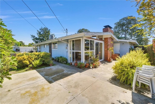 view of front of property featuring stucco siding, fence, and a chimney