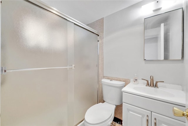 bathroom with toilet, a shower stall, and vanity