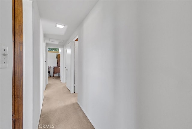 corridor featuring attic access and light colored carpet